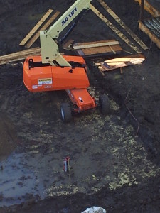 15000 pound man lift driving and sitting on a deck of polyurethane spray foam.